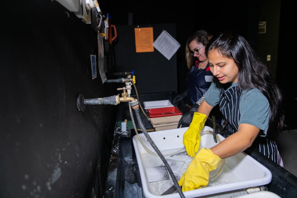 Photography students rinsing prints  in Jacksonville University’s Black and White analog darkroom. 