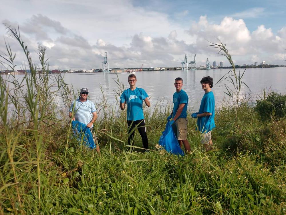 四名男性荣誉志愿者正在清理沼泽地.